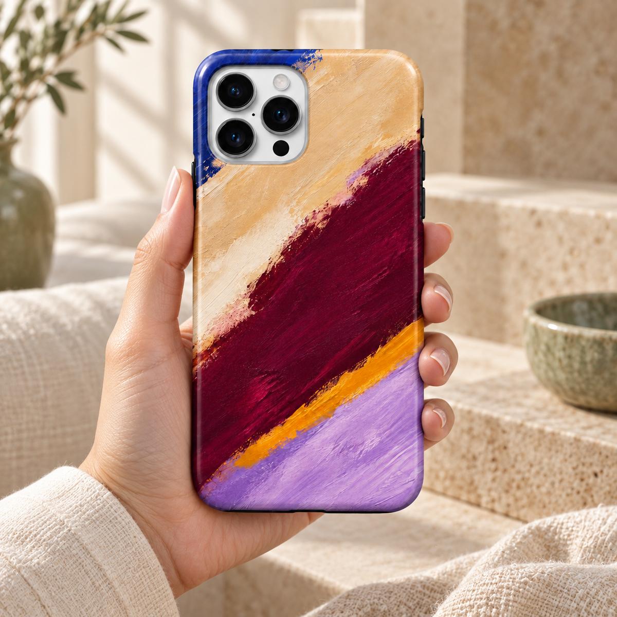 Coque Coups de pinceau tenue en main, motif abstrait imprimé dans un décor naturel crème et sauge.