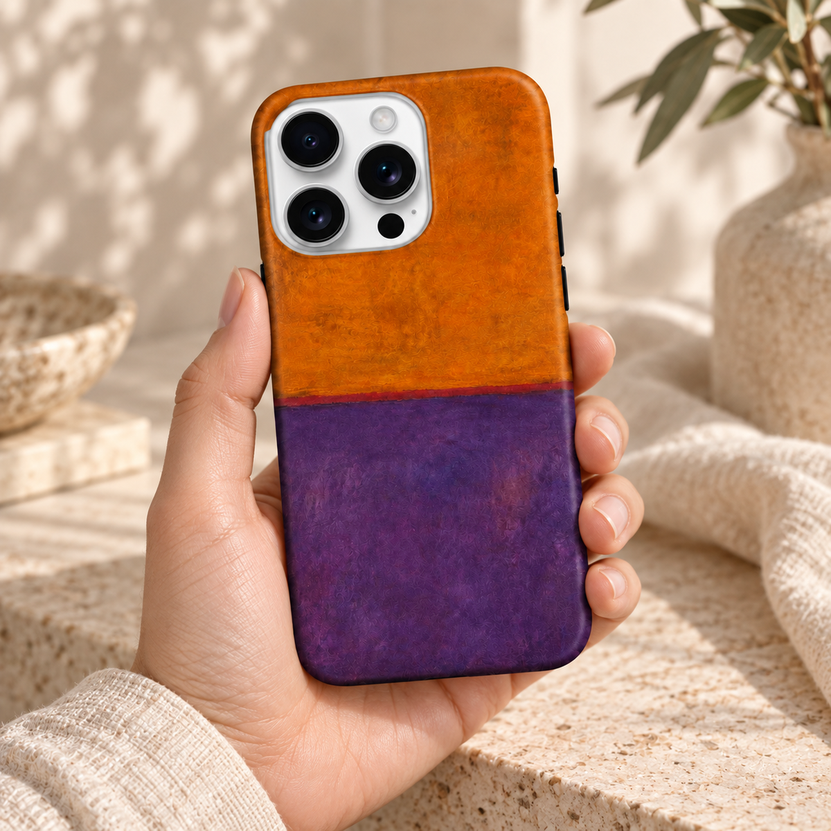 Coque Orange & Violet tenue en main, dans une lumière naturelle et un décor crème.