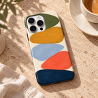 Coque Géométrie en couleurs posée sur une table en pierre naturelle à côté d’un café.