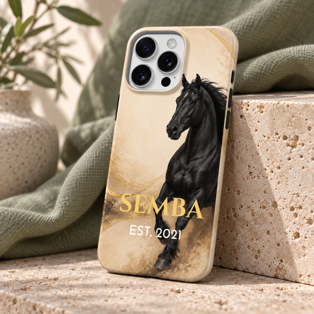 Vue de trois quarts de la coque cheval noir et doré SEMBA sur pierre claire et tissu sauge.