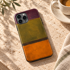 Coque Olive & Orange posée sur une table en pierre naturelle à côté d’un café.