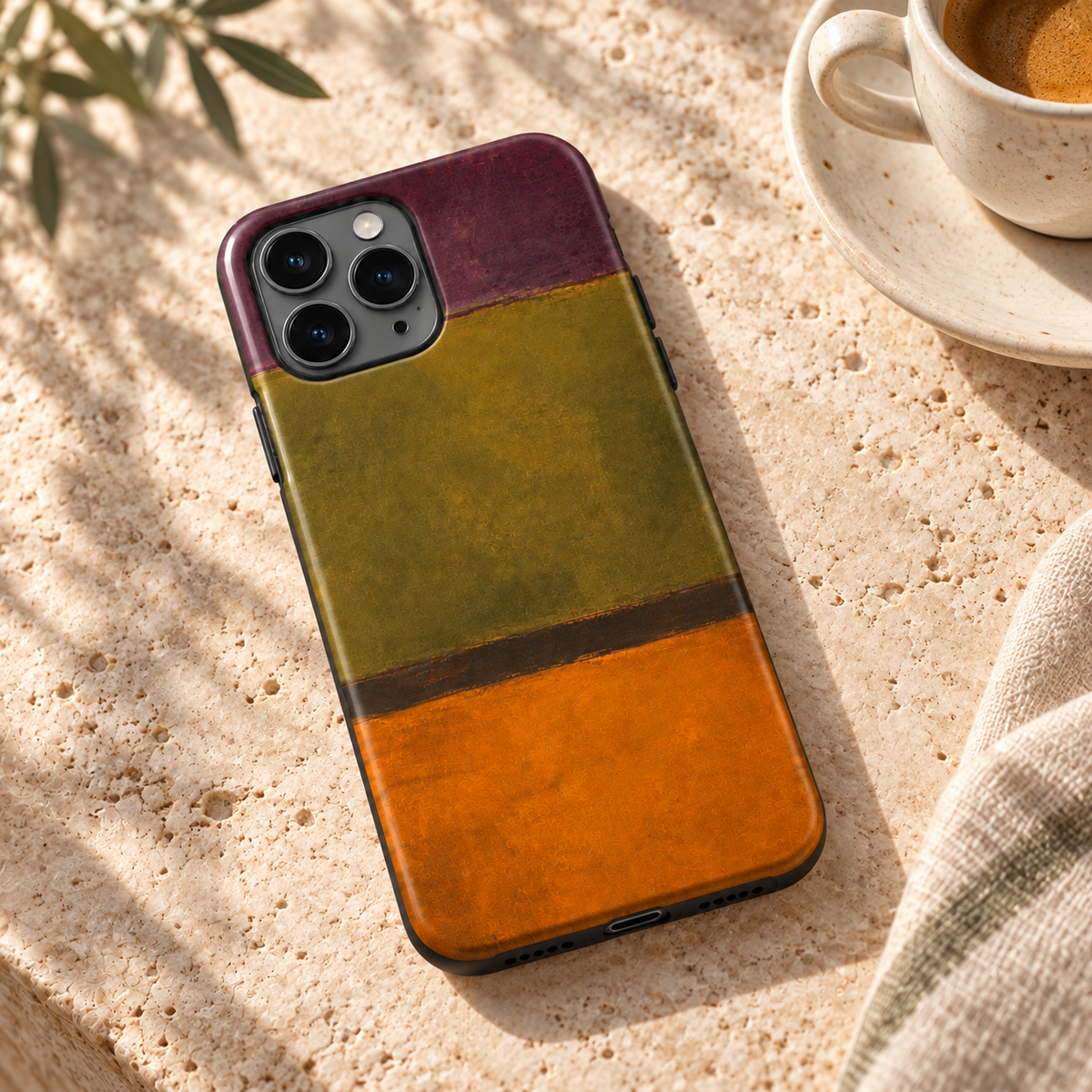 Coque Olive & Orange posée sur une table en pierre naturelle à côté d’un café.