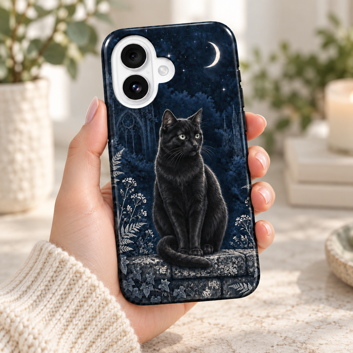 Chat noir & Lune — Nuit argentée — coque tenue en main dans un intérieur lumineux