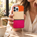 Coque Orange & Rose tenue en main dans un café, avec son motif abstrait imprimé.