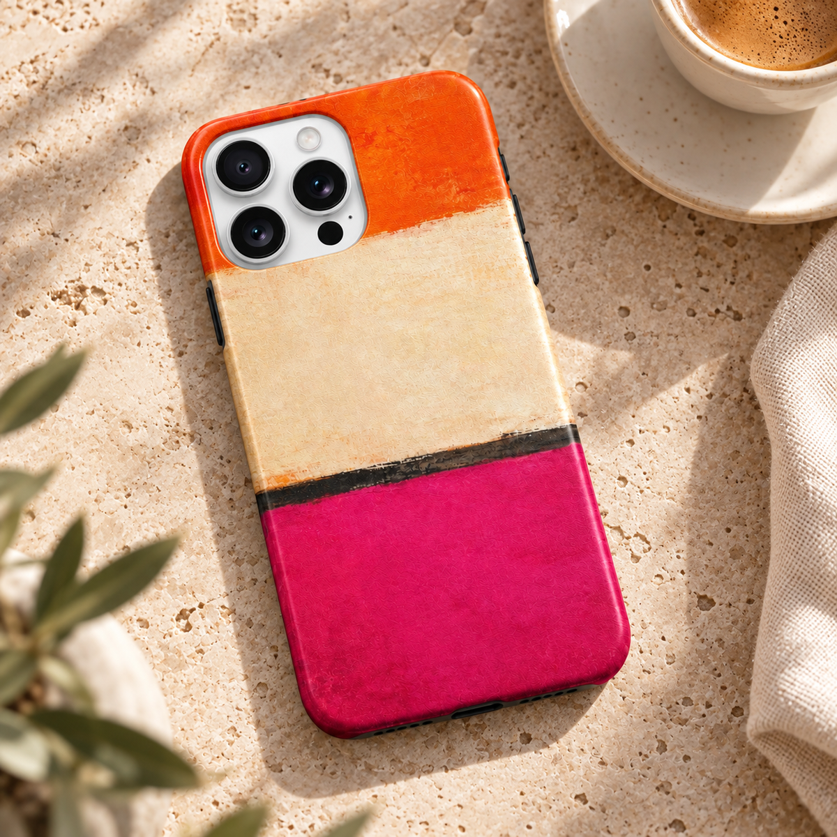 Coque Orange & Rose posée sur une table en pierre naturelle à côté d’un café.
