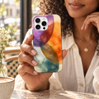 Coque Aquarelle vibrante tenue en main dans un café, avec son motif abstrait imprimé.