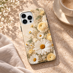 Coque Botanique jaune à marguerites et roses pâles, posée sur une table en travertin.