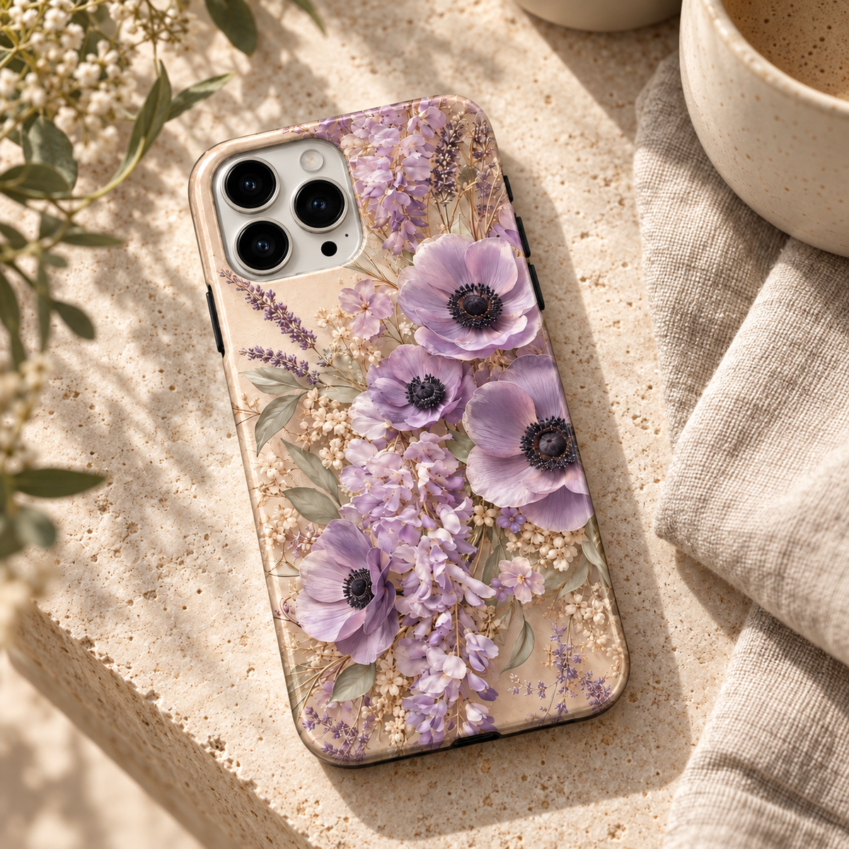 Coque Anémones lavande posée sur une table en travertin clair.