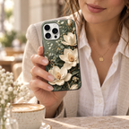Coque Magnolia sauge tenue en main, fleurs ivoire imprimées sur fond vert.