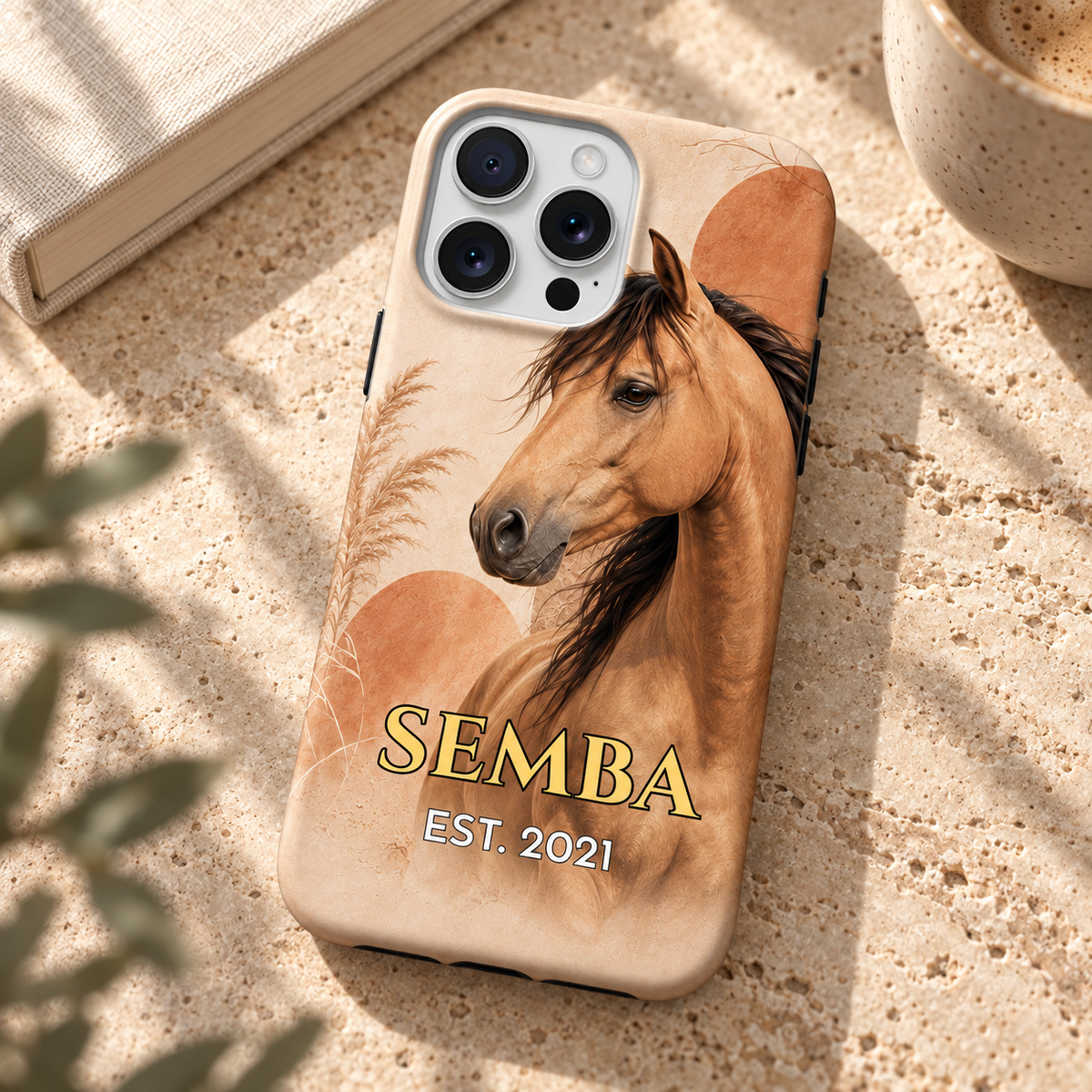Coque personnalisée cheval bohème SEMBA sur table en travertin près d’un livre et d’un café.