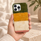 Coque Vert & Or tenue en main, dans une lumière naturelle et un décor crème.
